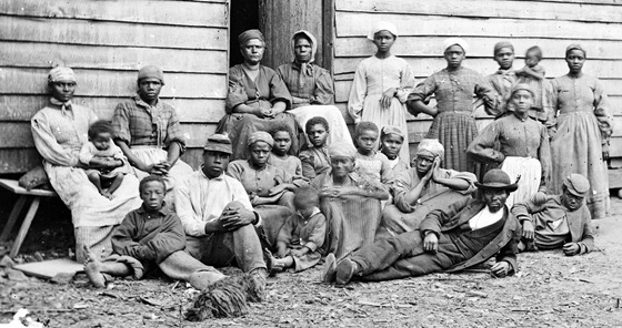 a group of slaves including men, women and children gathered outside a building at the Foller Plantation