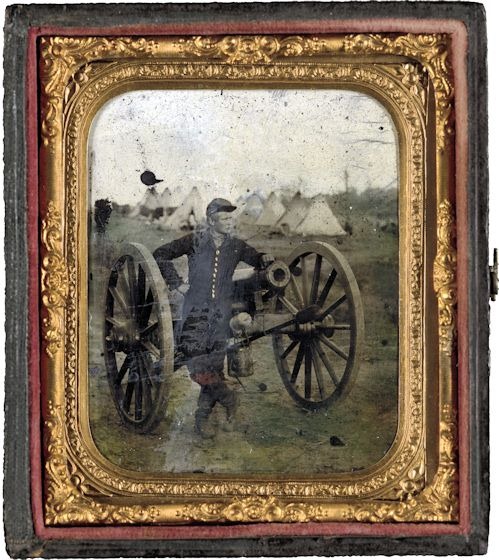 Unidentified soldier standing with Napoleon cannon in front of encampment