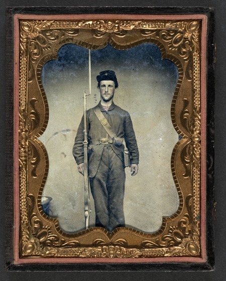 Unidentified soldier in Union frock coat and forage cap with cartridge pouch, ammunition pack, and bayoneted musket in frame