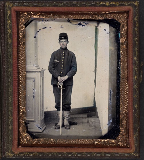 Unidentified young soldier in Union sack coat, forage cap, and white gaiters with sword -- fraamed